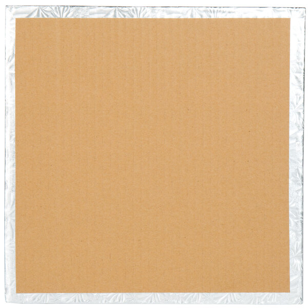 A close-up of a cardboard box with a white background. The cardboard is brown with silver foil on it.