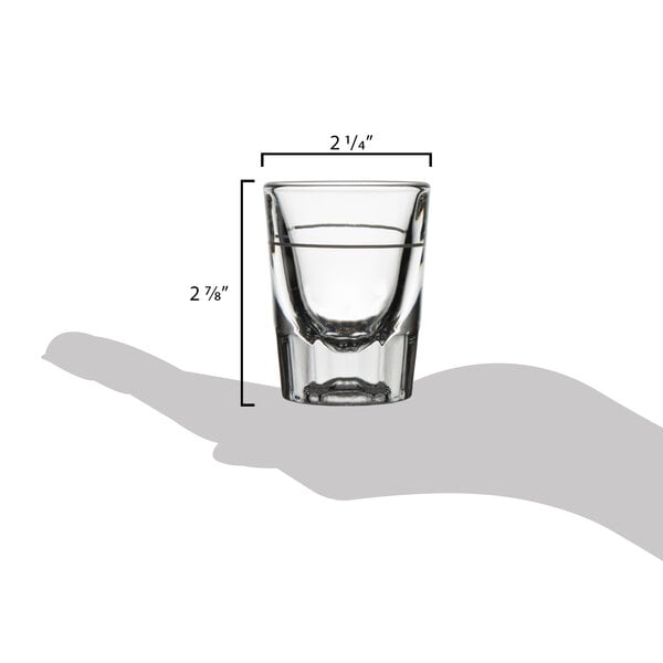A hand holding a Libbey fluted shot glass with a pour line.