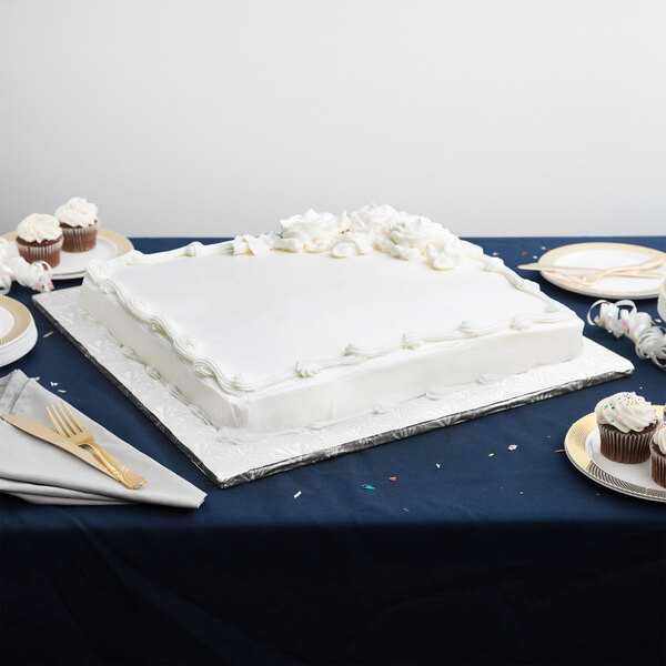 A white cake on a silver Enjay square cake drum on a table.