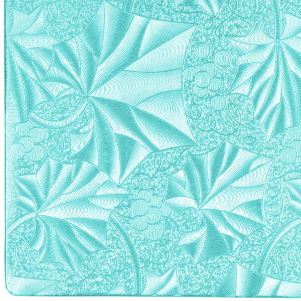 A close-up of a blue square cake drum with a patterned surface.