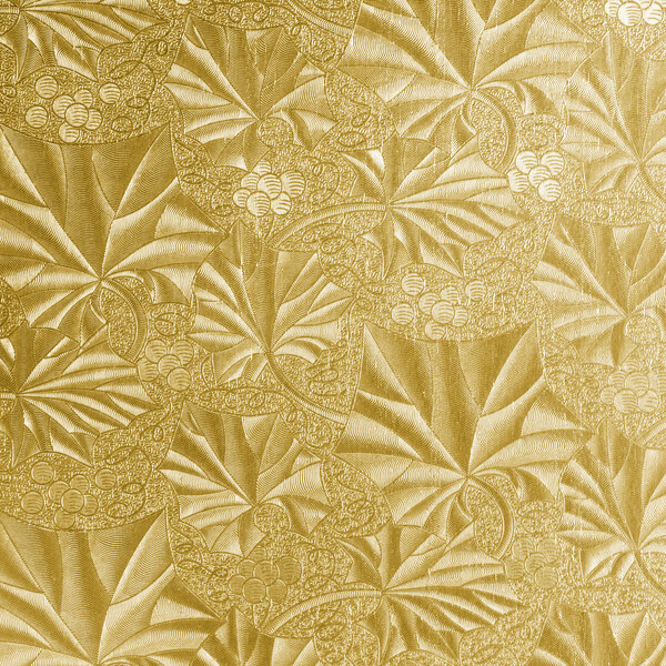 A white square cake drum with a gold patterned surface.