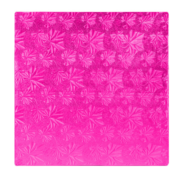 A white square cake drum with a pink surface and leaves on it.