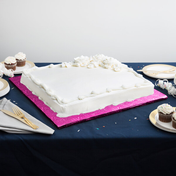 A white cake on a pink Enjay cake drum on a table.