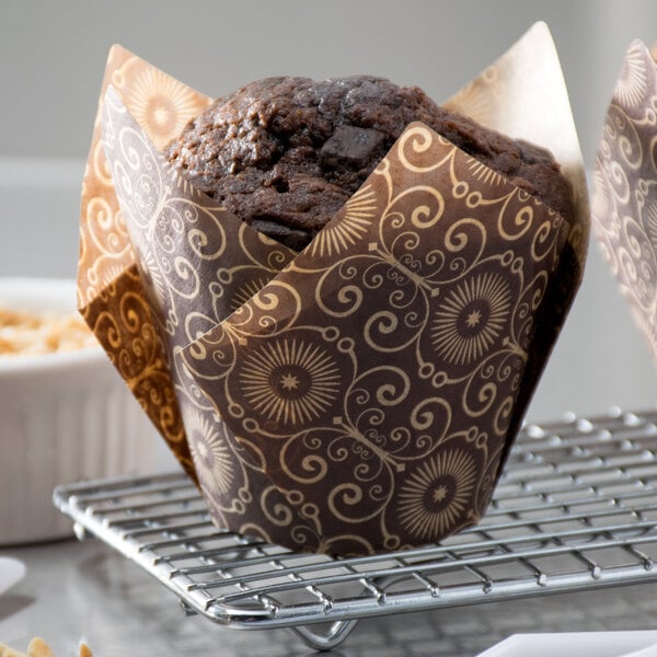 A muffin in a dark brown Mariposa print tulip baking cup.