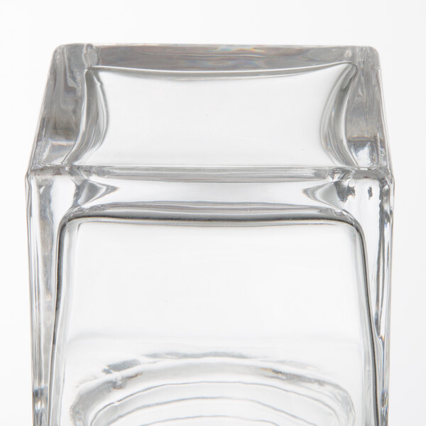 An American Metalcraft square glass cheese shaker with a stainless steel lid on a table.