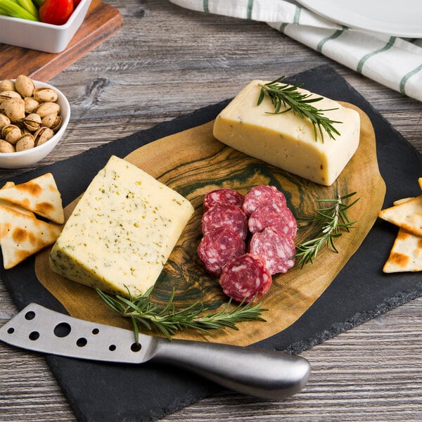 Black cheese board with a wood design cheese paper, with cheese, herbs, crackers, and sliced meat