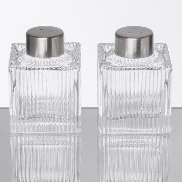 Two clear glass American Metalcraft ribbed square salt and pepper shakers with silver lids.