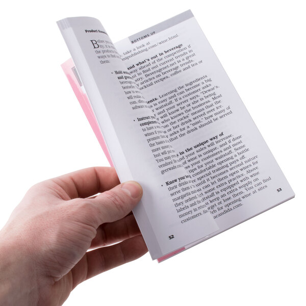A hand holding a book with a pink cover.