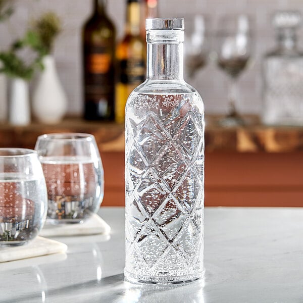 An American Metalcraft plastic diamond water bottle on a table with a glass of water.