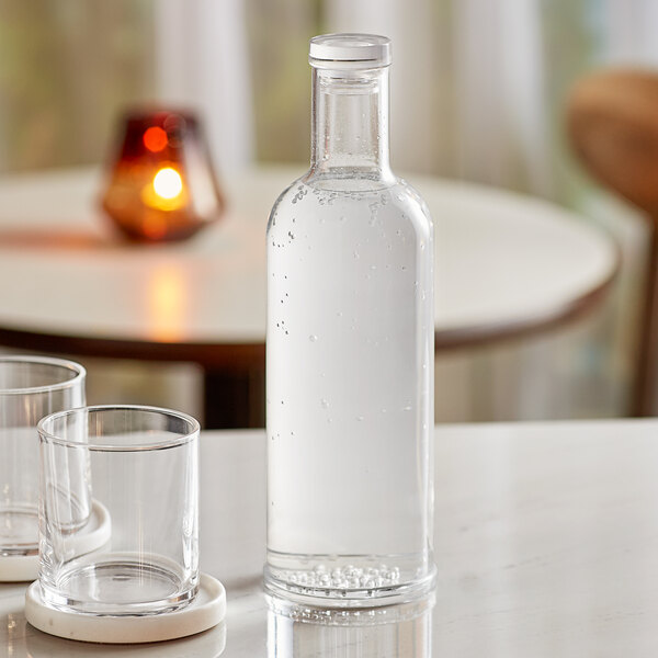 An American Metalcraft clear plastic water bottle and two glasses of water on a table.