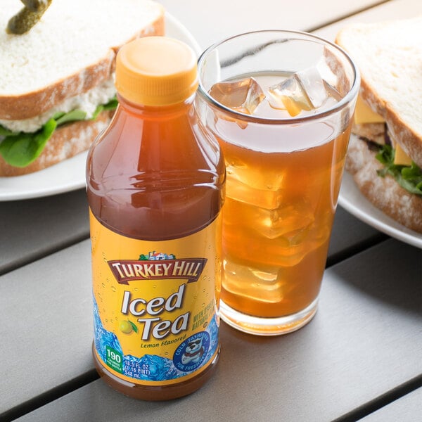 A sandwich and a glass of Turkey Hill Iced Tea on a table.