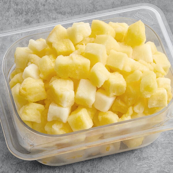 A plastic container filled with diced pineapple chunks.