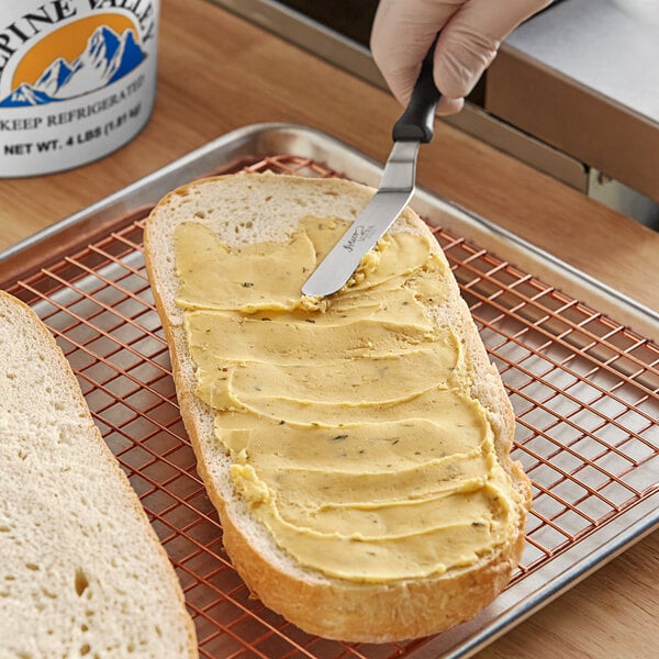 A person spreading Alpine Valley garlic butter on a piece of bread.