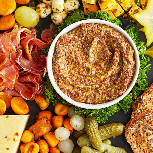 A plate of food with a variety of snacks including Domaine des Vignes French Whole Grain Mustard.