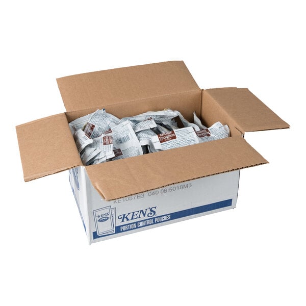 An open cardboard box filled with individually packaged condiment pouches.