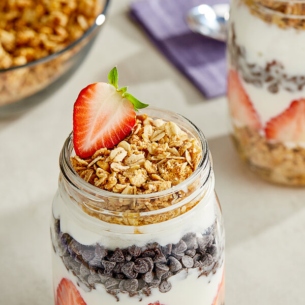 A jar of yogurt with Schlabach Amish Bakery Grand-Ola granola and strawberries.