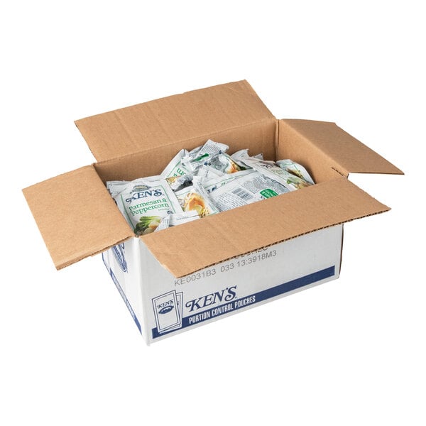 An open cardboard box containing multiple individual packets of Ken's Parmesan and Peppercorn dressing.