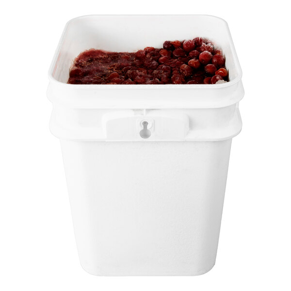 A white pail containing frozen red tart pitted cherries.