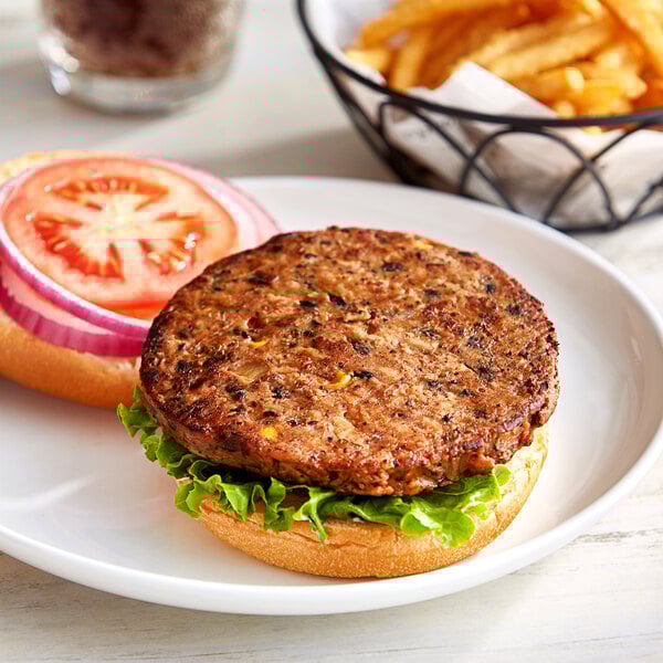 A Gardein black bean veggie burger on a plate with fries, onion, and tomato.