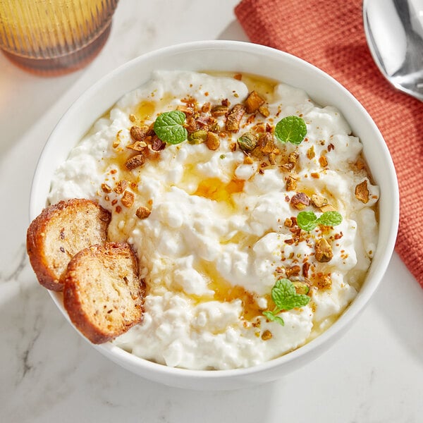 A bowl of Grassland small curd cottage cheese with croutons and a spoon.