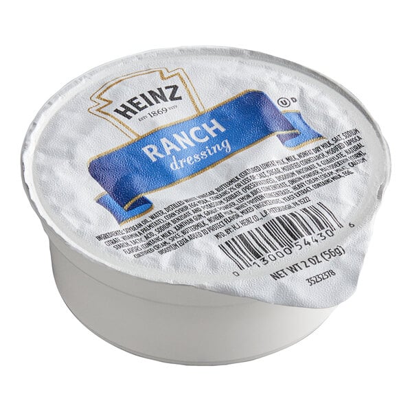 A small, sealed plastic cup of Heinz ranch dressing with a foil lid displaying the product name and barcode.