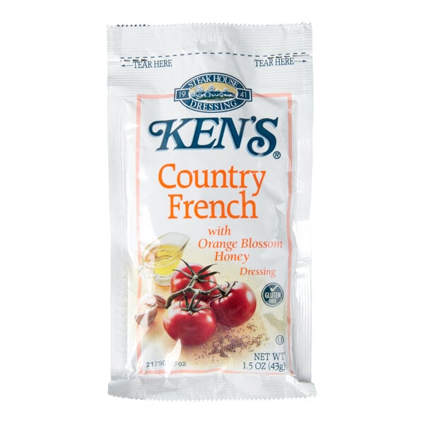 A single-serve packet of Ken's Country French with Orange Blossom Honey dressing, featuring images of tomatoes and a small glass of oil on the front.