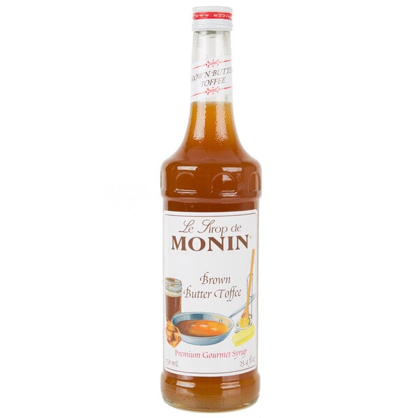 A bottle of Monin Brown Butter Toffee syrup with brown liquid inside.