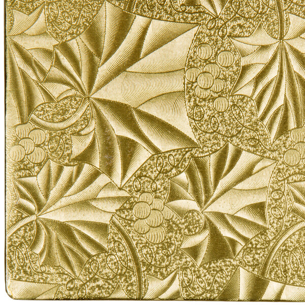 A close up of a gold Enjay square cake drum with a leaf pattern.