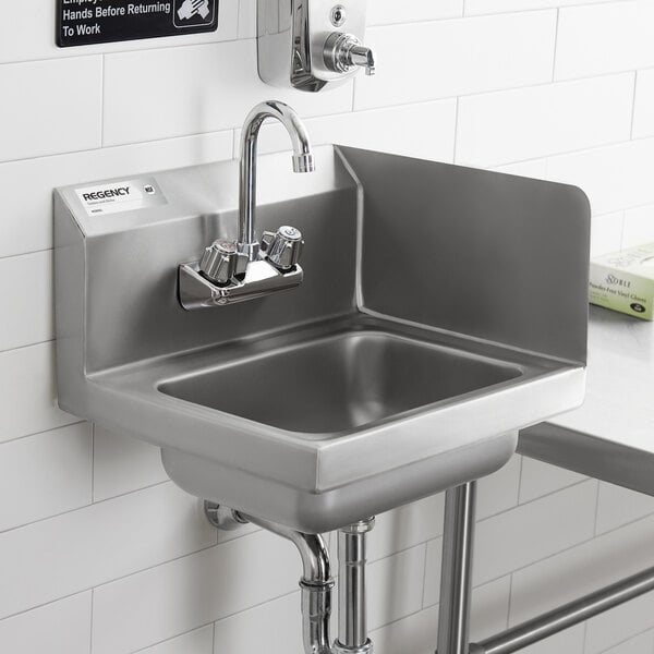 A stainless steel wall-mounted hand sink with a right-side splash guard and a gooseneck faucet, installed against a tiled wall.