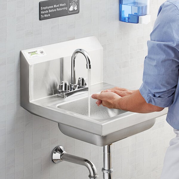 A person washing their hands in a Regency wall mounted hand sink.