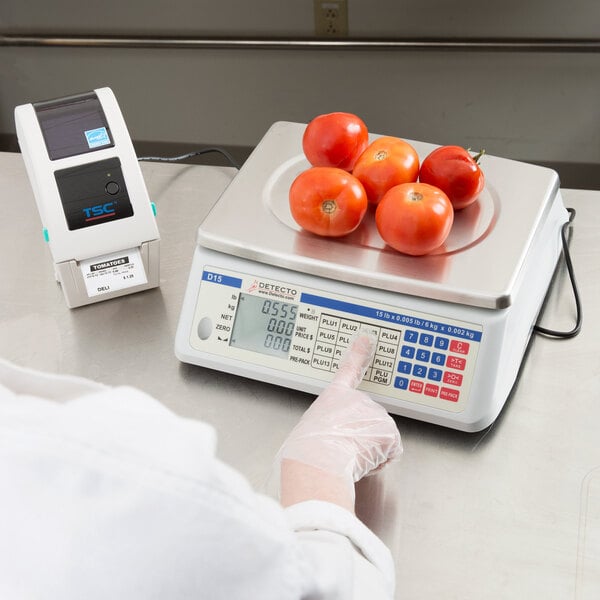 A person using a Cardinal Detecto digital price computing scale to weigh tomatoes.