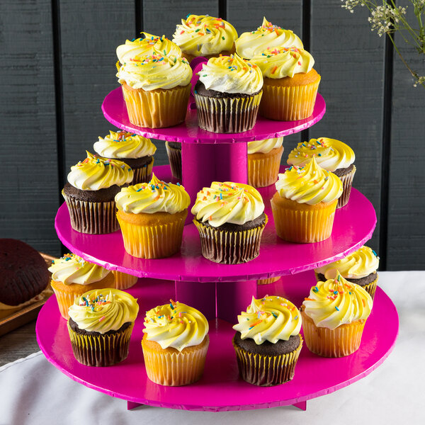 An Enjay pink three-tier cupcake stand with cupcakes on it.