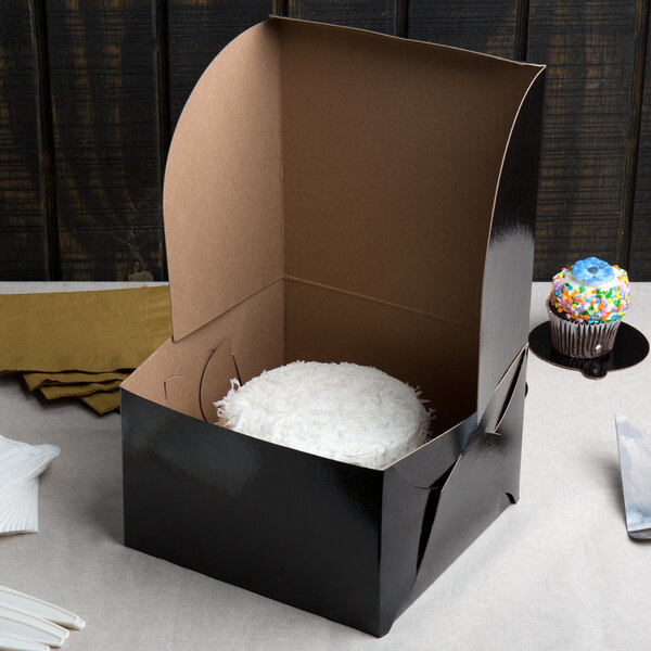 A black Enjay cake box with a white object inside.