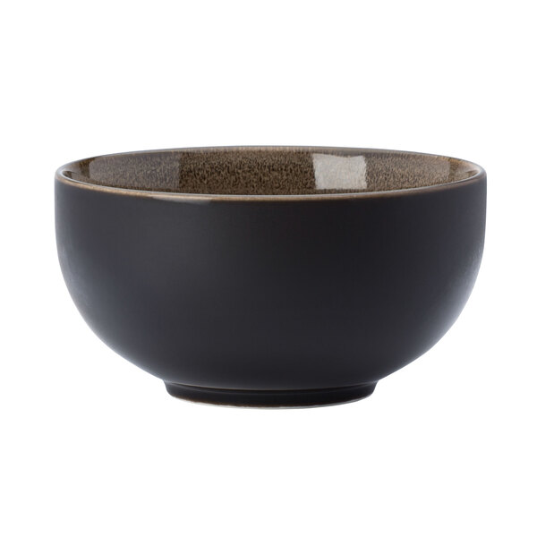 A white porcelain bowl with a black exterior and brown rim.