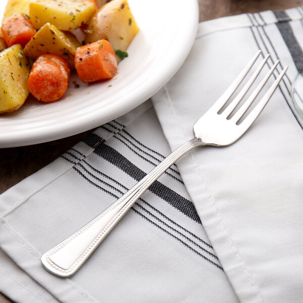 A Oneida Needlepoint stainless steel dinner fork on a plate with food.