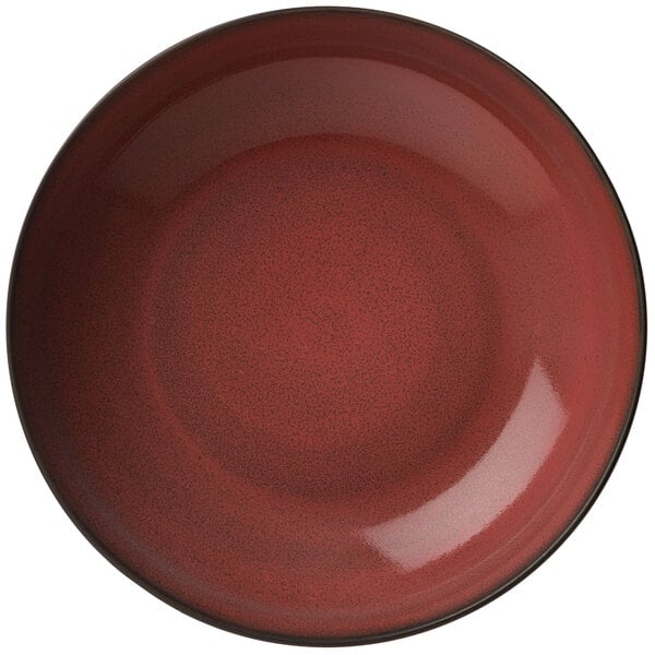 A white porcelain deep coupe plate with a red rim and black specks.