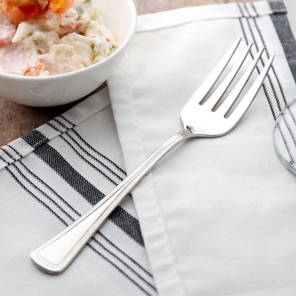 A Oneida Needlepoint stainless steel salad fork next to a bowl of salad.