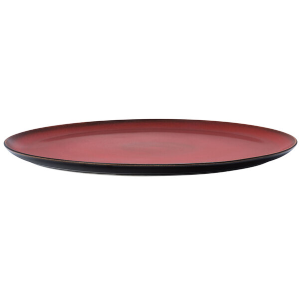 A close up of a red and white porcelain pizza plate with a black rim.