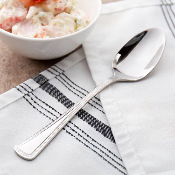 A Oneida Needlepoint stainless steel teaspoon in a bowl of food.