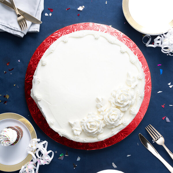 A white cake with white frosting on a red Enjay round cake drum.