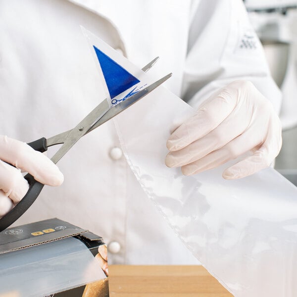A person cutting a plastic bag with scissors.