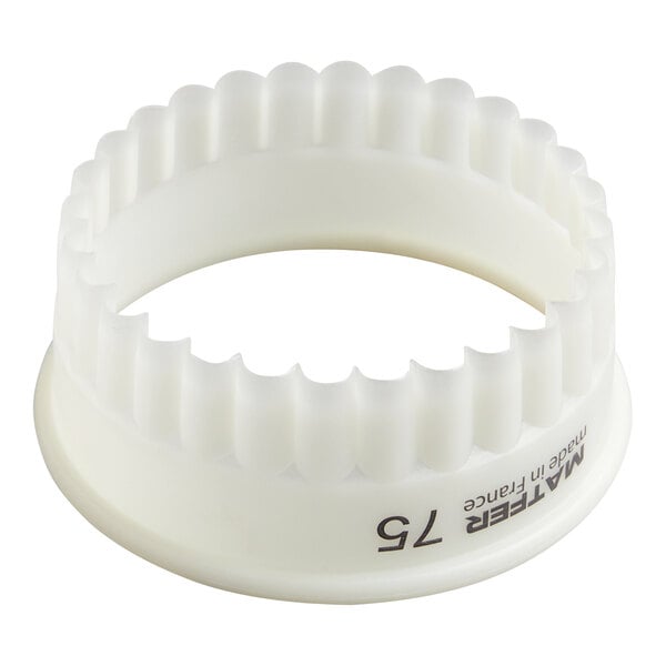 A white, round, fluted plastic cutter with a scalloped edge and the number 75 printed on the side.