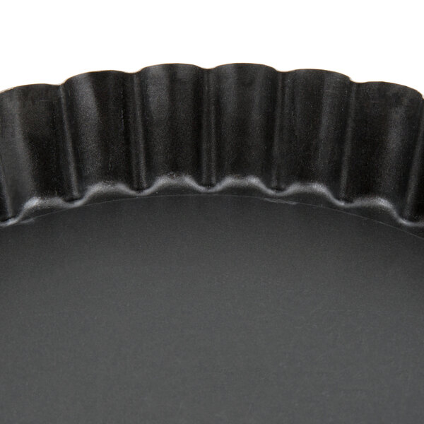 A black round Matfer Bourgeat non-stick fluted cake and tart pan with a wavy edge.