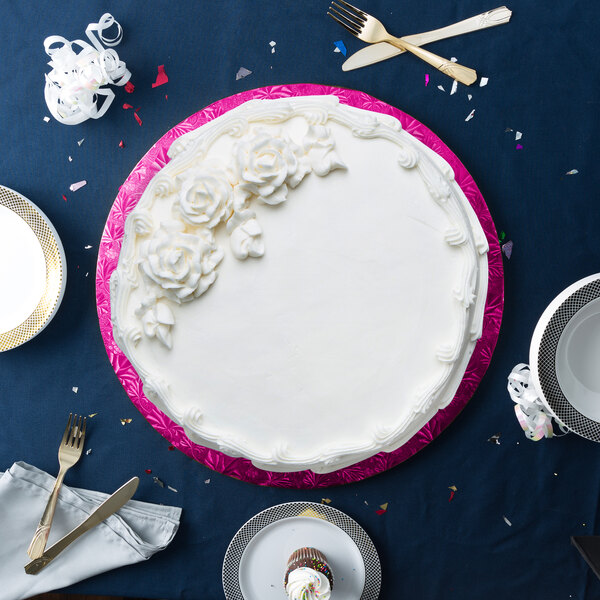 A cake with white frosting on a pink Enjay round cake board.