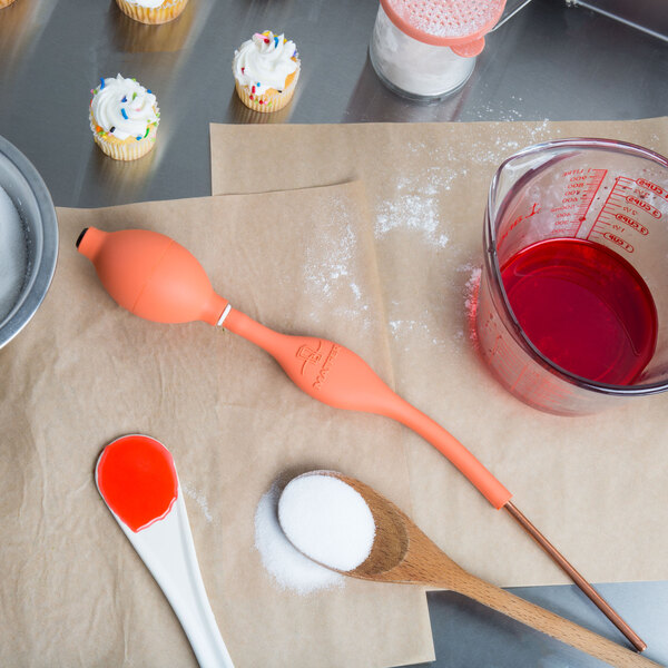 A Matfer Bourgeat Sugar Blowing Pump container with red liquid and a spoon.