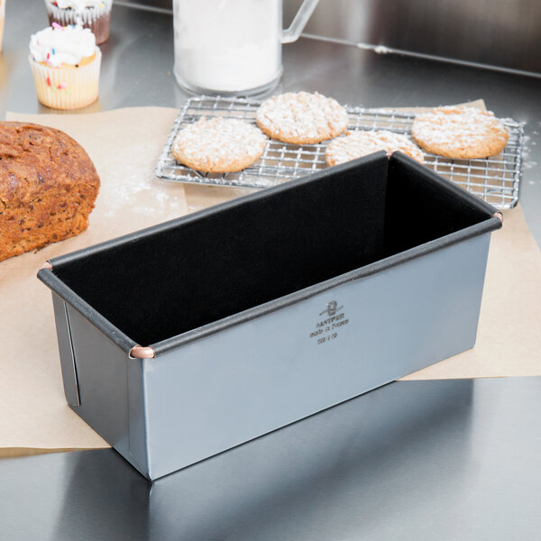 A Matfer Bourgeat non-stick bread loaf pan on a counter with a loaf of bread.