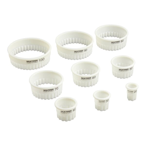 Nine white, round, fluted pastry cutters of varying sizes are arranged in a group, each labeled with a number indicating its diameter.