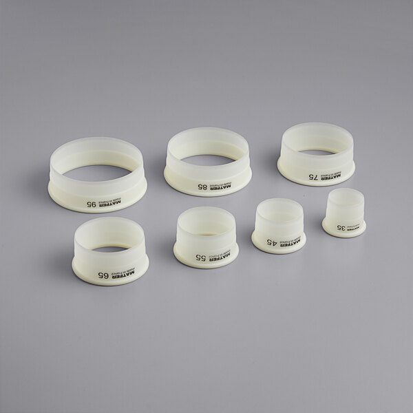 A group of white plastic Matfer Bourgeat round dough cutters with black text.