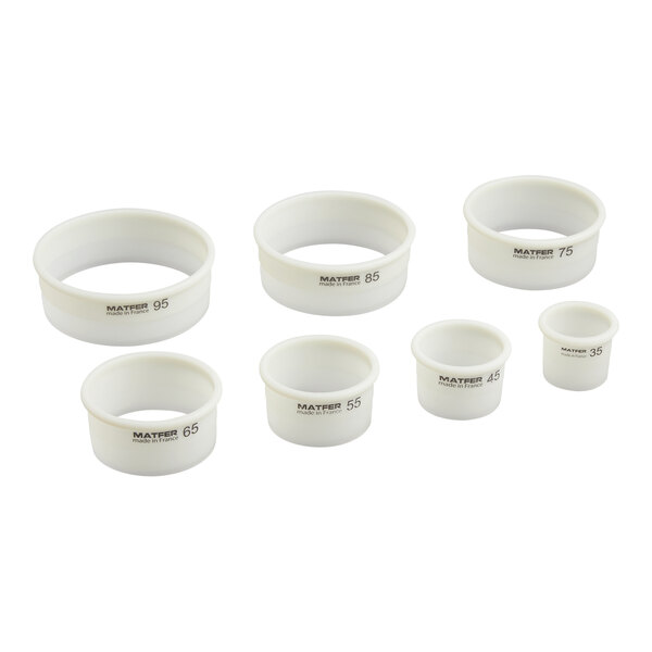 Seven white, round pastry cutters of varying sizes are arranged in two rows on a white background.