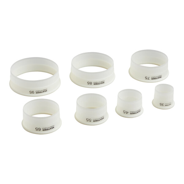 Seven white, round, plastic pastry cutters of varying sizes are arranged in two rows on a white background.